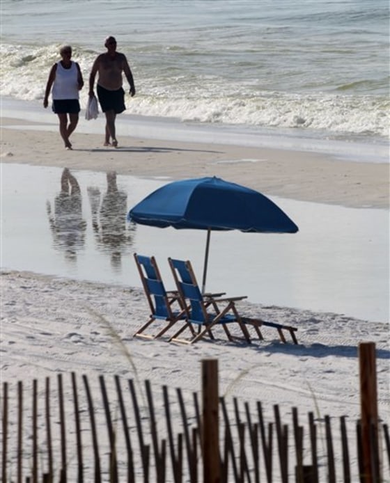 People walk past empty beach chairs in Destin, Fla., on Sunday. Some hotels and condominium owners along the Gulf say their business is down by 50 percent.